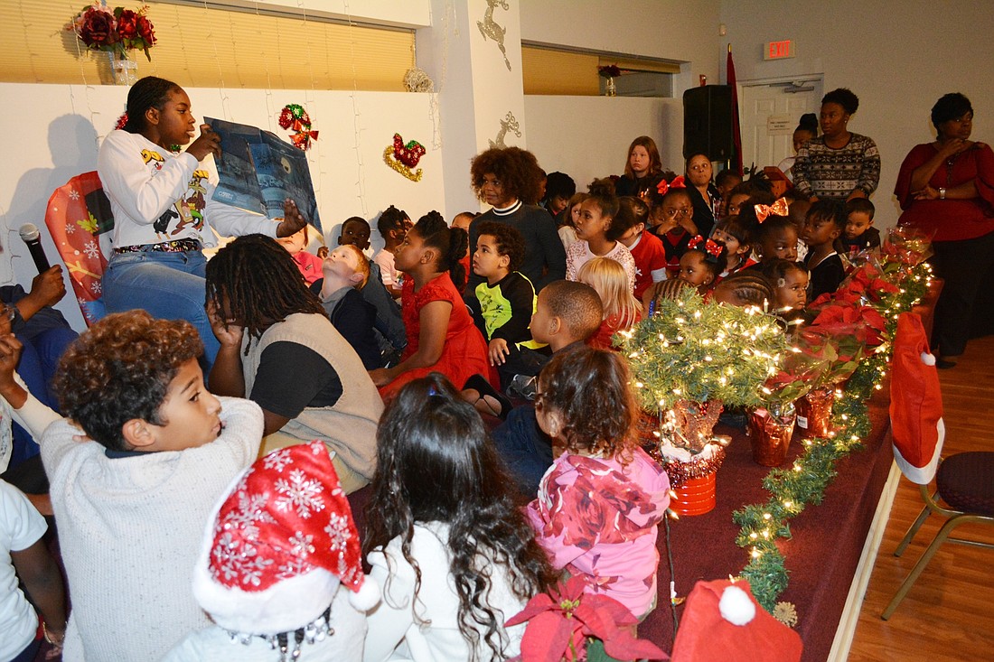 Edina Brown reading "The Night Before Christmas" to the children at the AACS gift-giving event. Photo by Edmund Pinto, Jr.