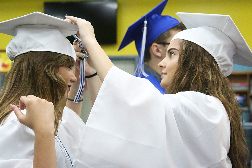 Amanda Rushton helps Mercedes Connelly put on her cap before a mock ceremony in May 2018. File photo by Paige Wilson