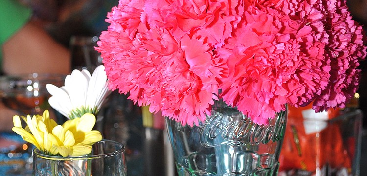 Old school Coca-Cola glasses outfitted with flowers and straws posed as centerpieces.