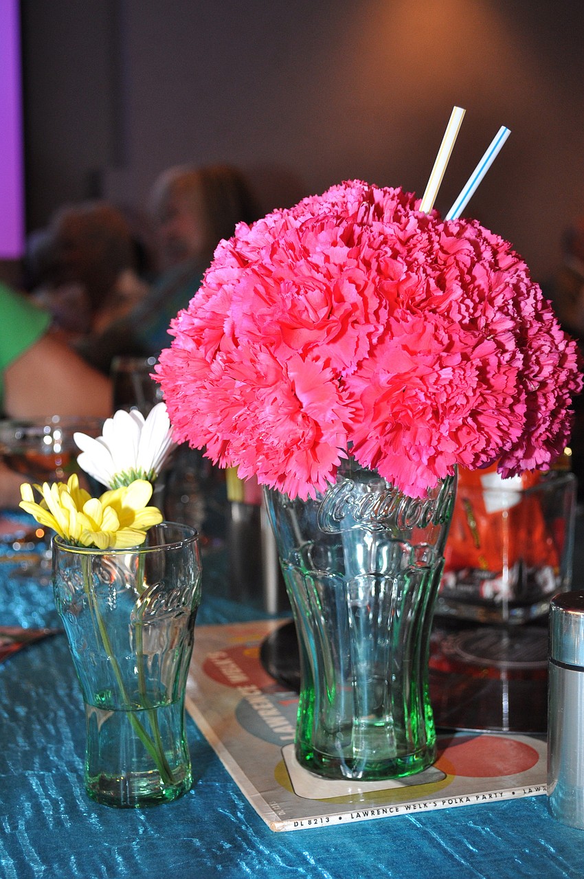 Old school Coca-Cola glasses outfitted with flowers and straws posed as centerpieces.