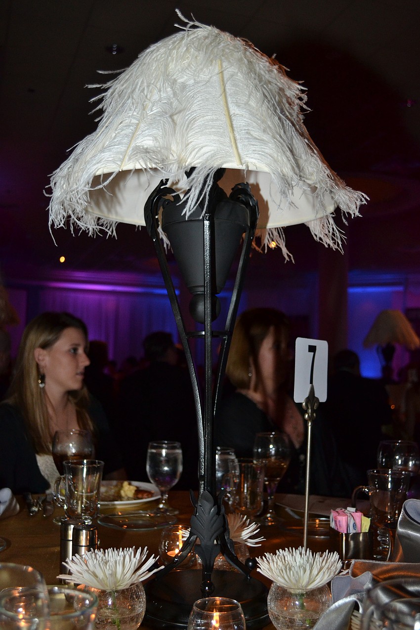 Tables were set with feathered lamp centerpieces.