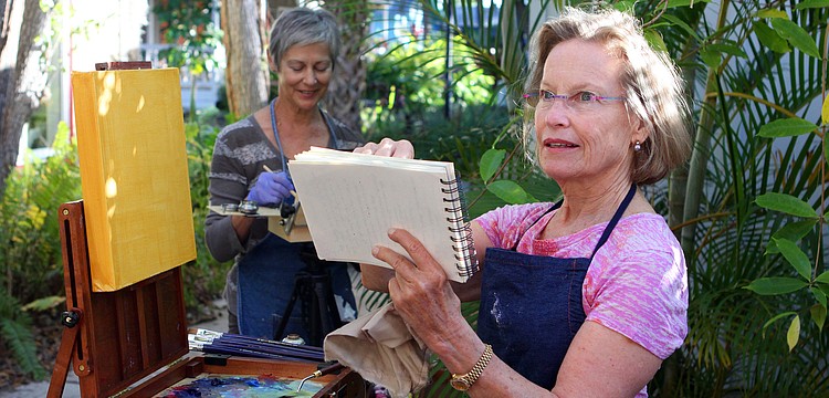 Carol Baker sketches out a drawing of her painting in a notebook before applying the sketch to the canvas.
