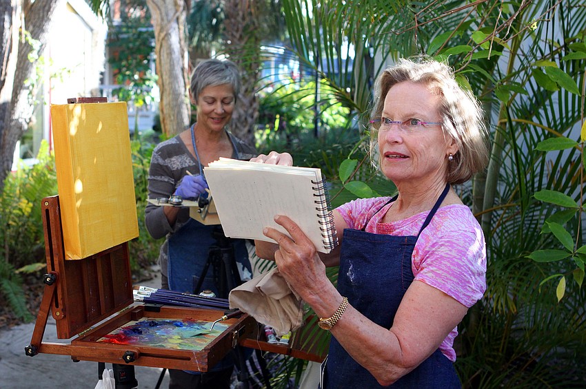 Carol Baker sketches out a drawing of her painting in a notebook before applying the sketch to the canvas.