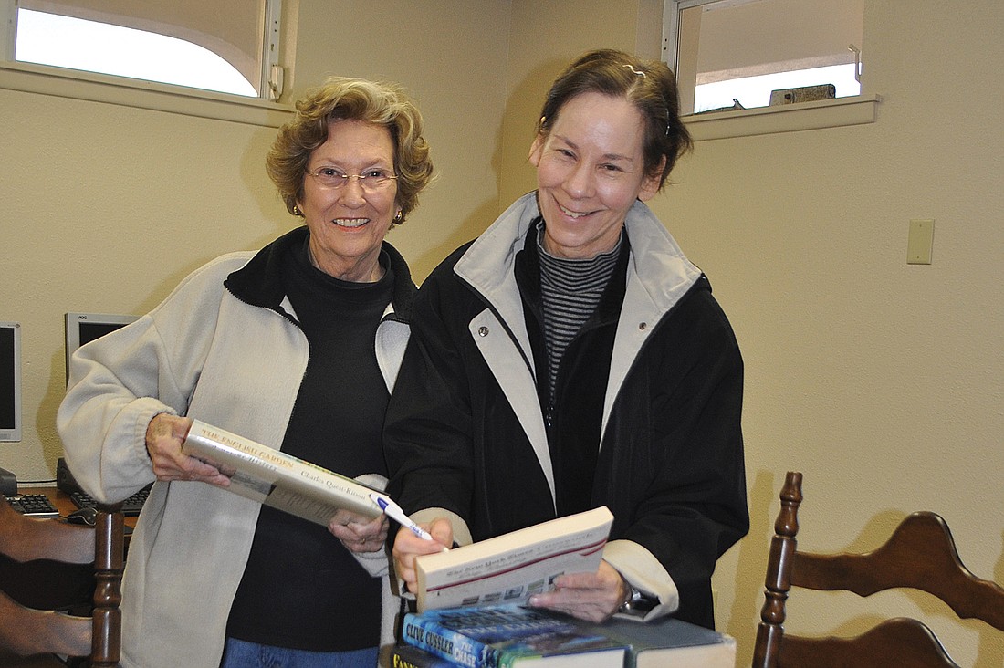 Patty Bower and Karen Fors mark books that will be for sale. Photo by Dora Walters