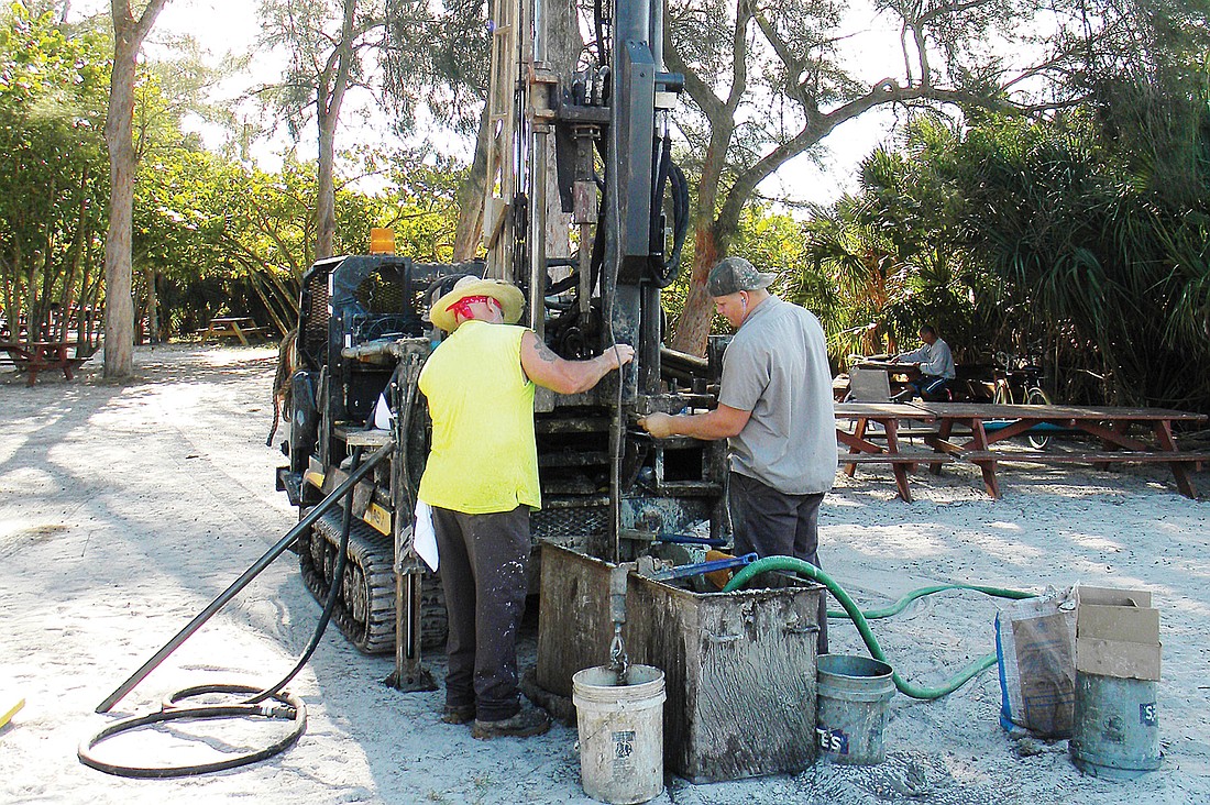 Robert Shuey and Joe Shaw, employees of Tierra Inc., check on the depth of the water table Jan. 31 in one section of the Siesta Public Beach Park. Photo by Norman Schimmel.