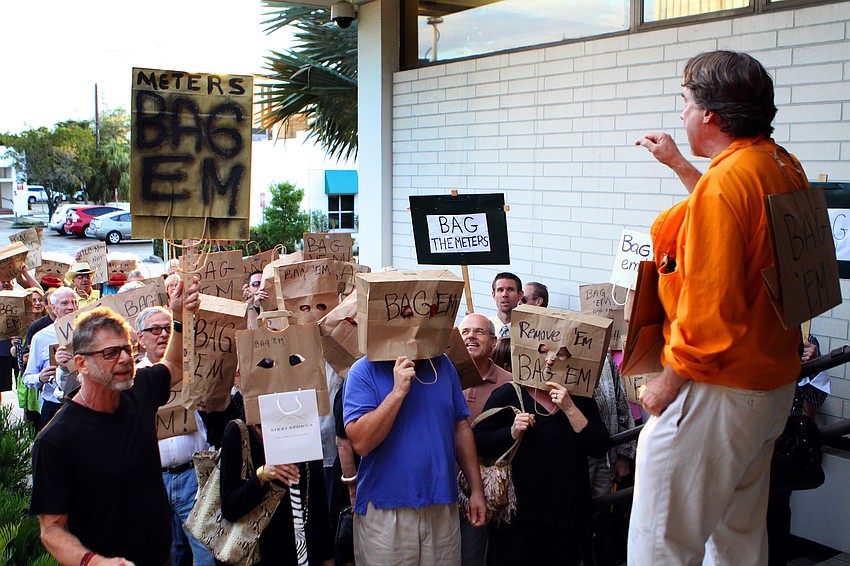 Baggers stand outside City Hall wearing bags on their heads and listening to James Derheim, Monday, Feb. 6.