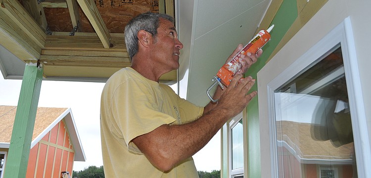 Rick Obeid, of New Panel Homes, today caulks one of five new dog cottage at Honor Animal Rescue's Ranch on Lorraine Road. Volunteers from T.J. Maxx painted the structures Wednesday.
