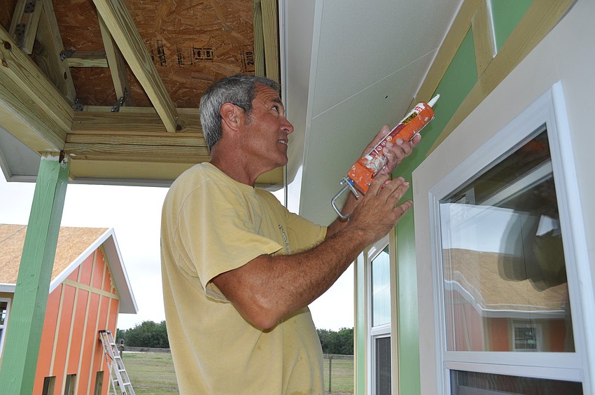 Rick Obeid, of New Panel Homes, today caulks one of five new dog cottage at Honor Animal Rescue's Ranch on Lorraine Road. Volunteers from T.J. Maxx painted the structures Wednesday.