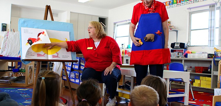 Nancy Velazquez reads "Brown Bear Brown Bear" while Michele Guffanti wears stuffed, velcro animals from the book on the story apron.