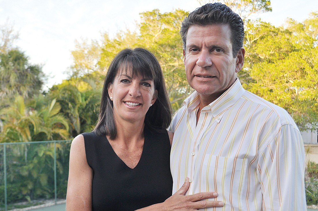 Janine and Dorian Irizarry stand on their porch overlooking the tennis courts on which they play.
