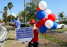 Chris Powers held up a sign, Friday, March 23, from a rally that happened earlier in the day by the Kissing Statue on 41.