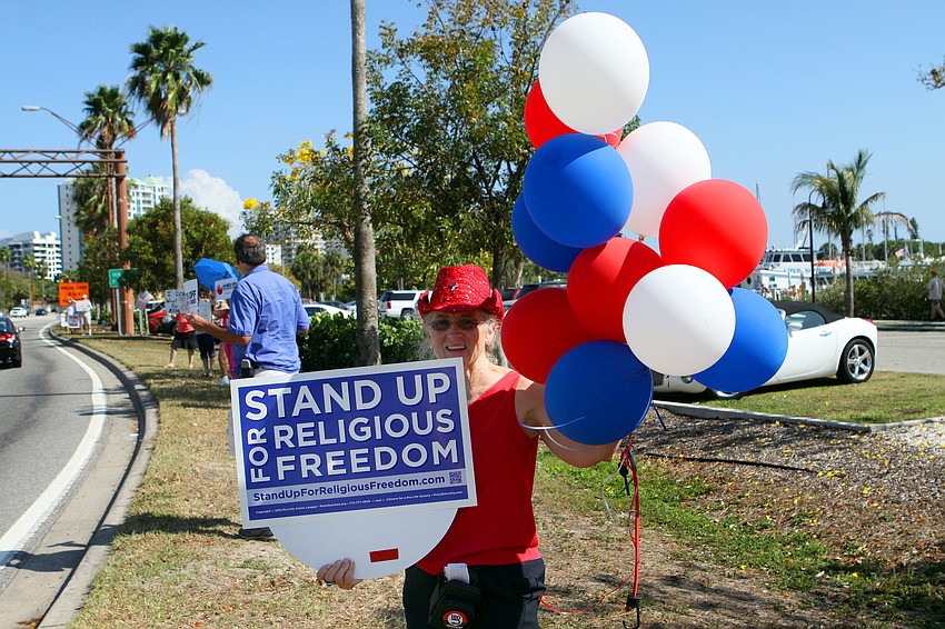 Chris Powers held up a sign, Friday, March 23, from a rally that happened earlier in the day by the Kissing Statue on 41.