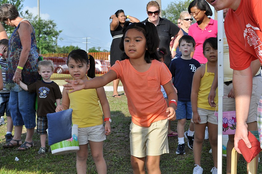 Five-year-old Miranda Juarez tries her hand at the beanbag toss while her three-year-old cousin Natalie Sanchez looks on.