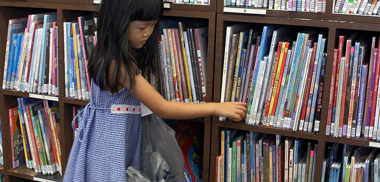 Felicity Lui, 4, reaches for an egg on the bookshelf.