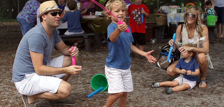 JJ Weatherbie, 3 Â½, makes bubbles while his father, Jonas, mother, Brittany, and brother, Braxton, 2 Â½, look on, Saturday, March 31, at the Face Autism Egg Hunt at Ashton Elementary.