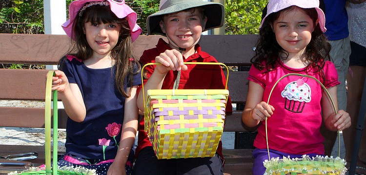 Isabella Sanchez, 4 Â½, Zack Sanchez, 7, and Portia Sanchez, 4 Â½, sit together on a bench while they wait for their turn to go find Easter eggs.