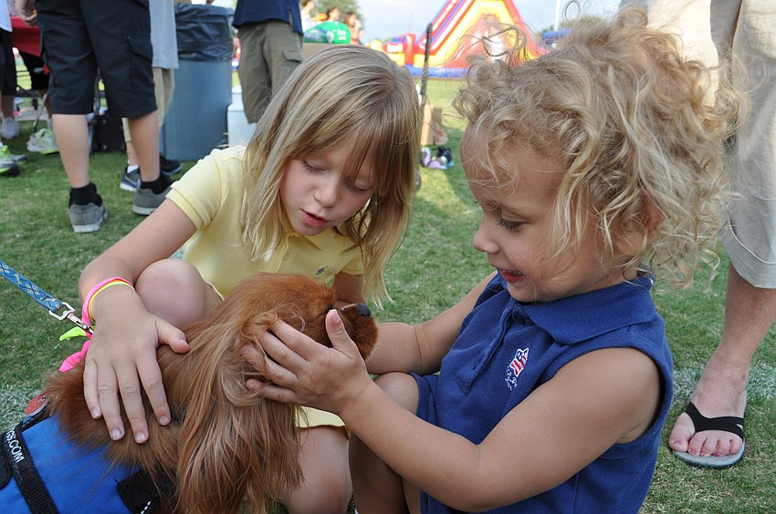 Katy Vale, front, and her sister Lily, behind, took great interest in Rex, a therapy dog.