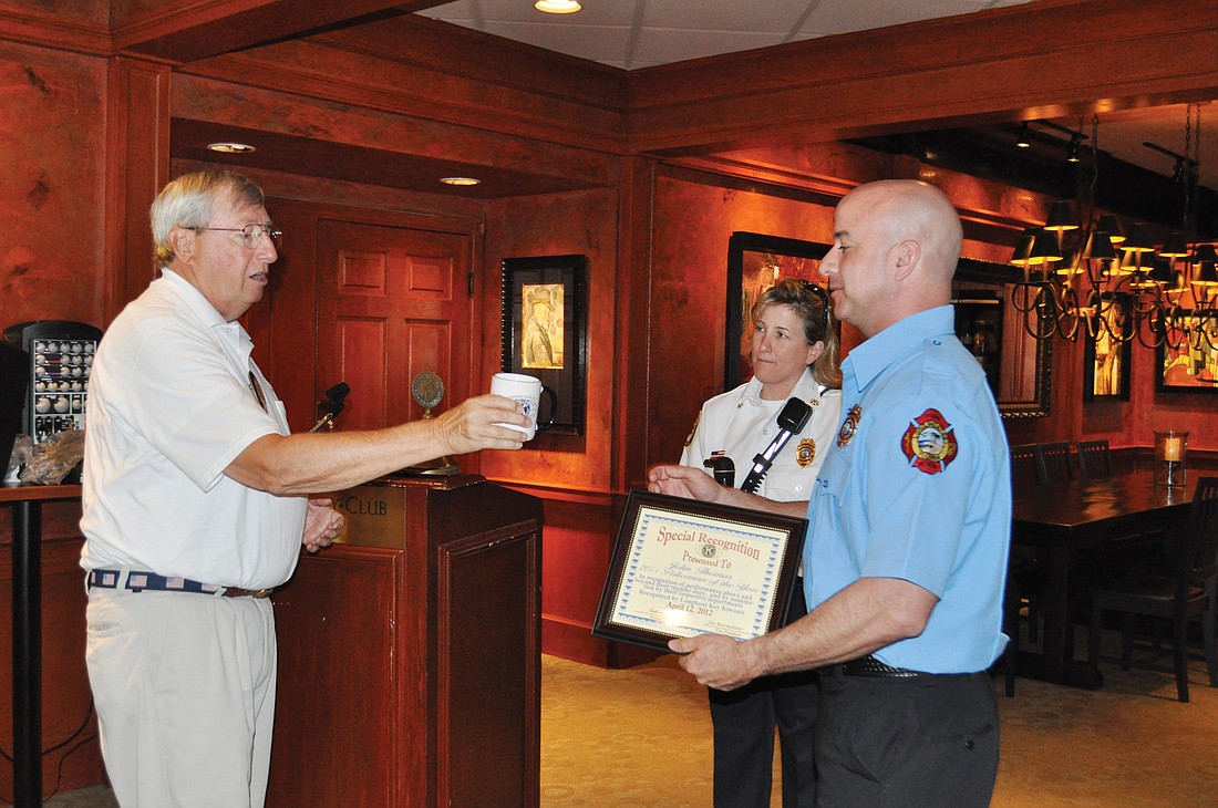 President John Wild presents a certificate and coffee mug to firefighter Jim Reynolds, with Dep. Chief Sandi Drake standing by.