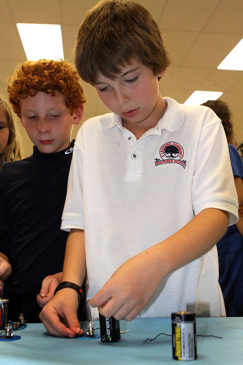Zeban Kaiser, 10, gets a light bulb to light up using wires and a battery.