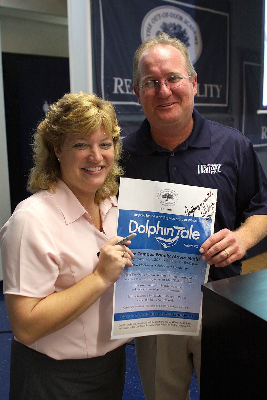 Lisa Cheney, marine science teacher, poses with Dan Strzempka and the poster he signed, Friday, Jan. 20, at Out-of-Door Academy.
