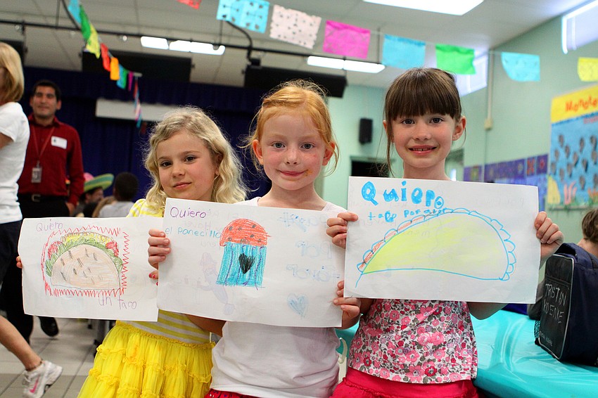 Ella Pepper, 7, Payton Rietow, 7, and Olivia McDaniel, 6, show off the menus they made for El Restaurante Bay Haven.