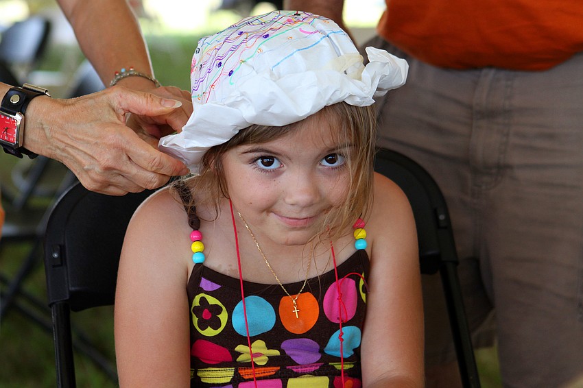 Mary Foster, 7, has help finishing up her paper hat, Saturday, March 24, at Springfest.