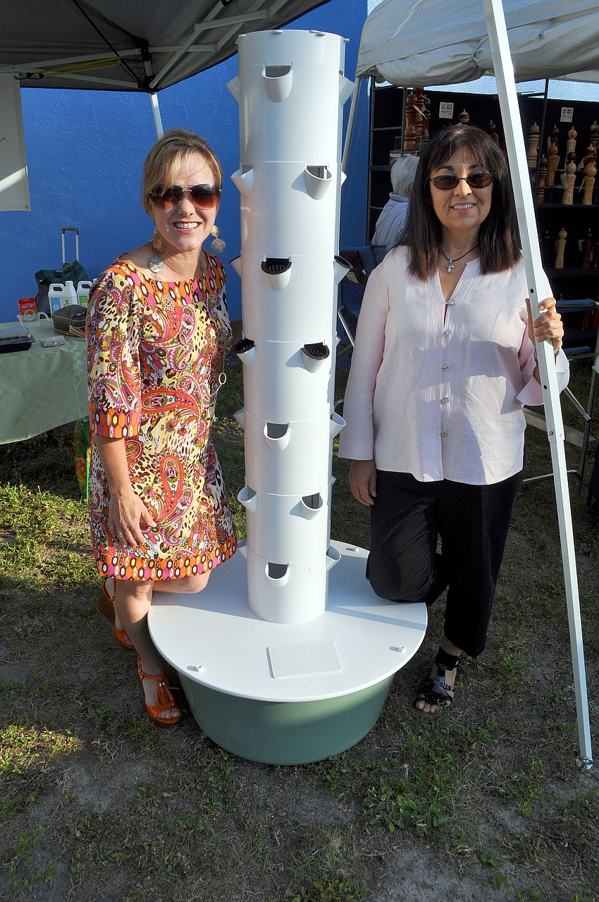 Caryn Patterson and Lillian Morales pose next to the Tower Garden.