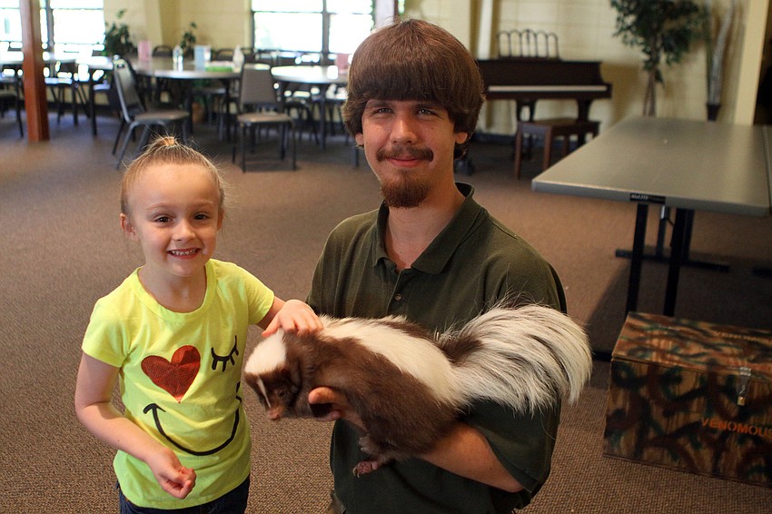 Violet Walsh poses with Jeremiah Nichol and Jungle Gardens' skunk, Mocha, Thursday, Jan. 12, inside the Parish Hall at St. Boniface. Walsh got a kiss on the hand from Mocha.
