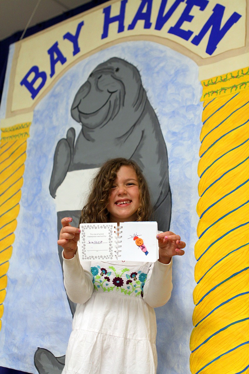 Summer Backhurst, 5, poses up on stage with her finished book, 