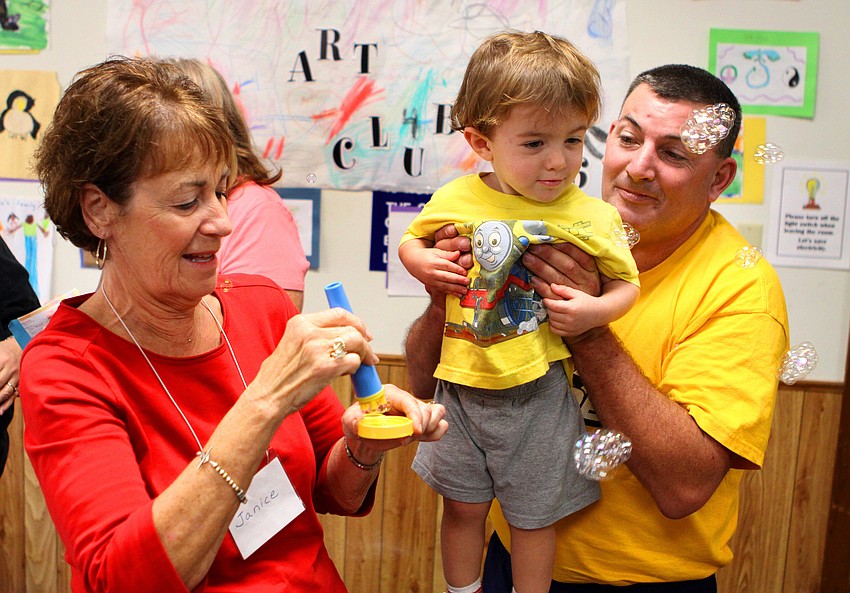 Jeffery Lewis holds his son, Zachary, 22 mos., up to look at the bubbles that were blown by Janice Frankel.