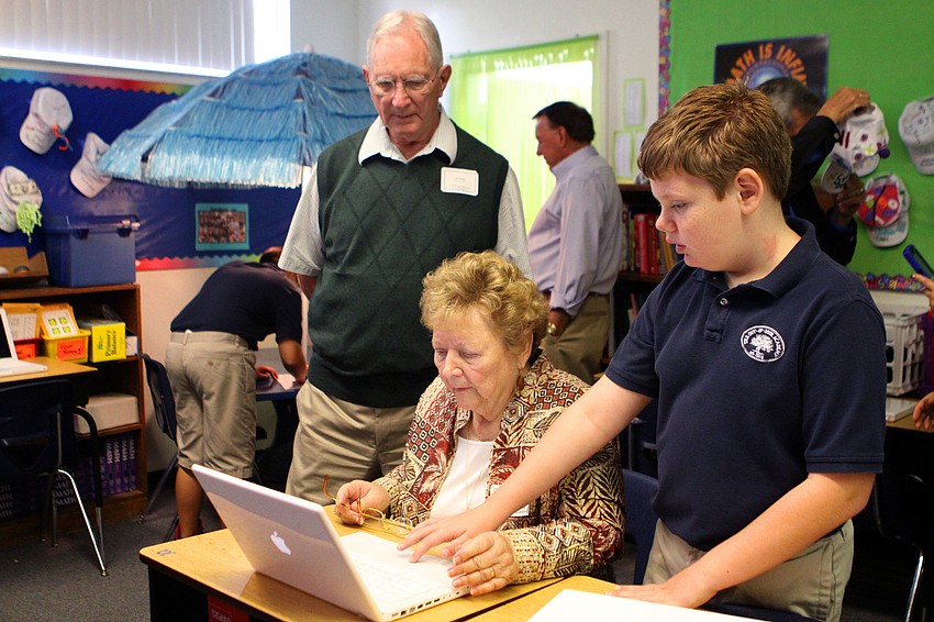 Cameron Hiller, 6th grade, shows his grandparents, Jim and Mary Long, some of his schoolwork on his computer.