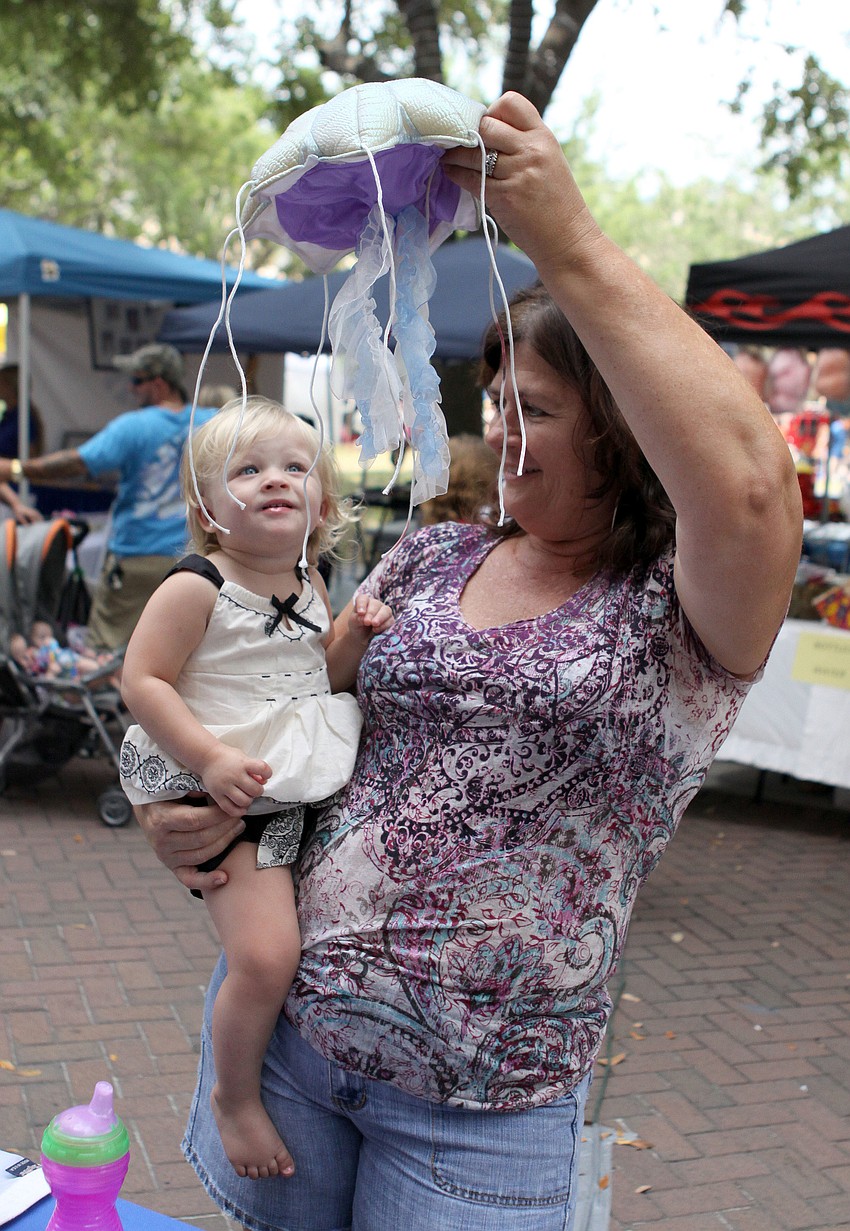 Cindy McRee shows her granddaughter, Lena McCree, a stuffed jellyfish from the Mote Marine table.