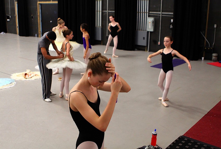 Nikki Jennings puts some extra hairspray in her hair during rehearsal while the rest of the group practices and get into their costumes.