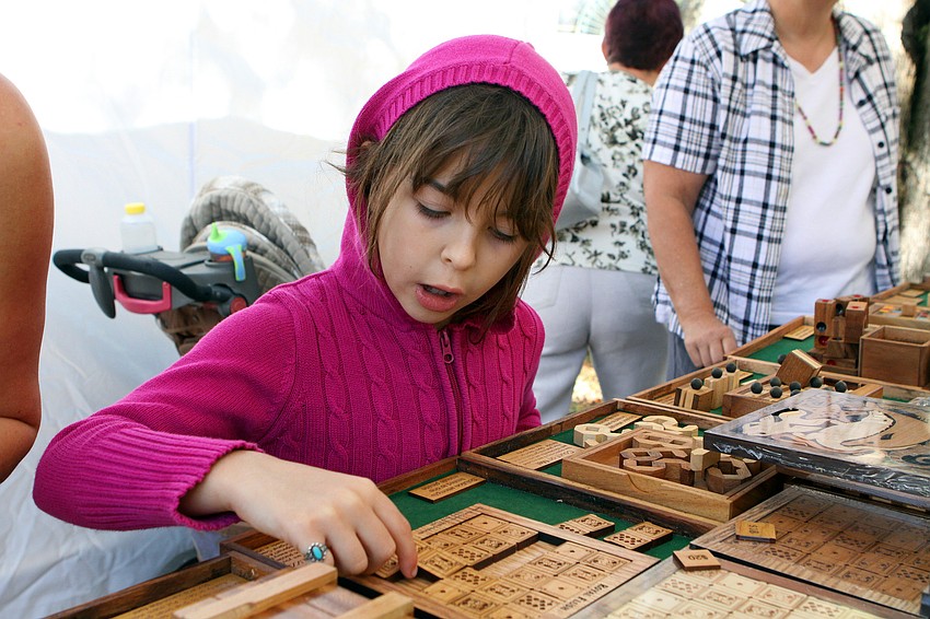 Picassa Stanton, 7, plays with one of the many wooden, handcrafted puzzles made by Brain Teaser Puzzles.