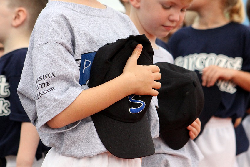 A young ball player places his cap over his heart during the National Anthem.