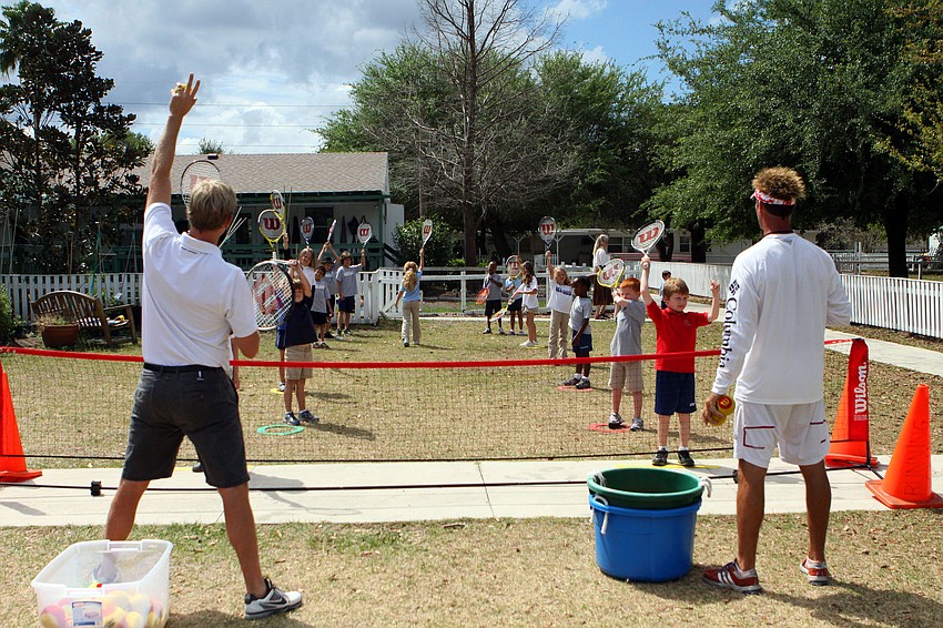 Students raise their racquets high in the air to show that they are paying attention and ready to play.