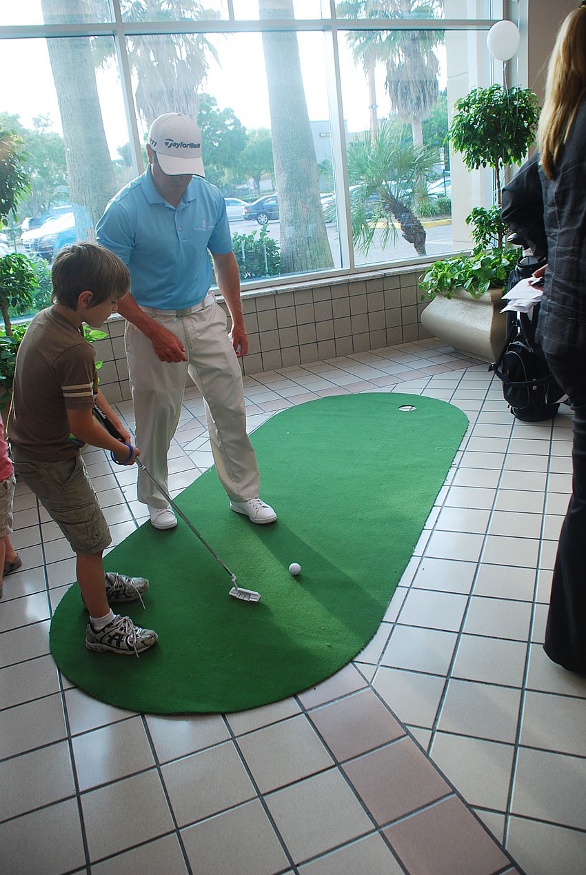 Daniel Asanakas playing mini-golf at the Ritz-Calrton Members Club booth