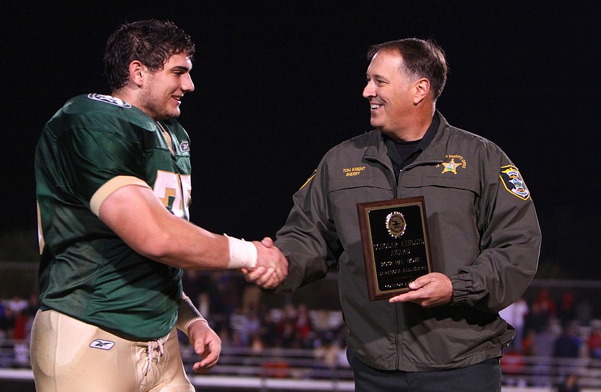 Connor Kruge, 75, shakes hands with Sheriff Tom Knight. Kruge was awarded the Sarasota County's Scholar Athlete Award.