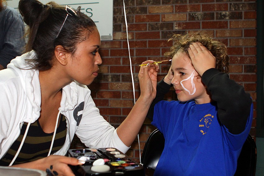 Randi Etienne of Ringling College of Art and Design paints Connor Rutherford's face.