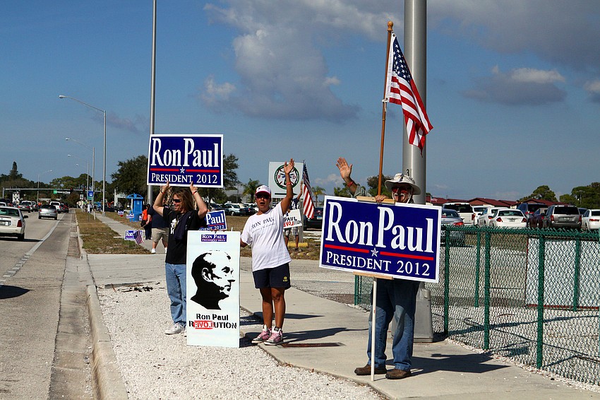 Ron Paul supporters stand out on the sidewalk by Dolphin Aviation waving at cars.