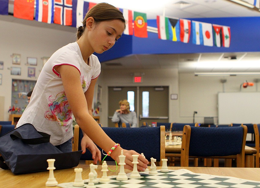 Brooke Witte helps to set up the chessboards before the Tournament of Hearts, Saturday, Feb. 11, in the library at Phillippi Shores Elementary.
