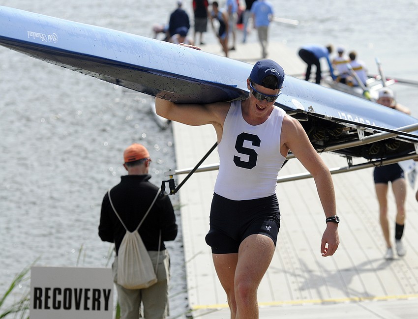 Sixteen-year-old Ben Delaney carries his boat up out of the water following the boys high school 2x race, which he and his teammate won.