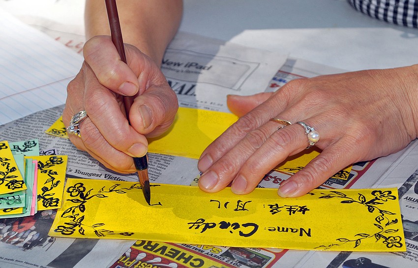 Ai Zhuang Chan writes out a woman's name in Chinese calligraphy.