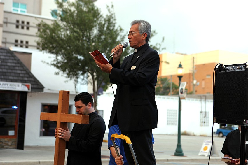 Deacon Humberto Aliva from St. Jude Catholic Church reads in Spanish at the 4th Station, Friday, April 6, on Main Street.