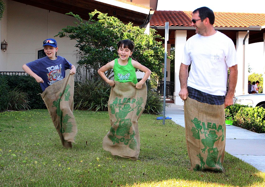 Joe Condron, 8, Faith Hutchinson, 7, and Ed Hutchinson race one another in a potato sack race, Saturday, April 7, at St. Michael the Archangel.