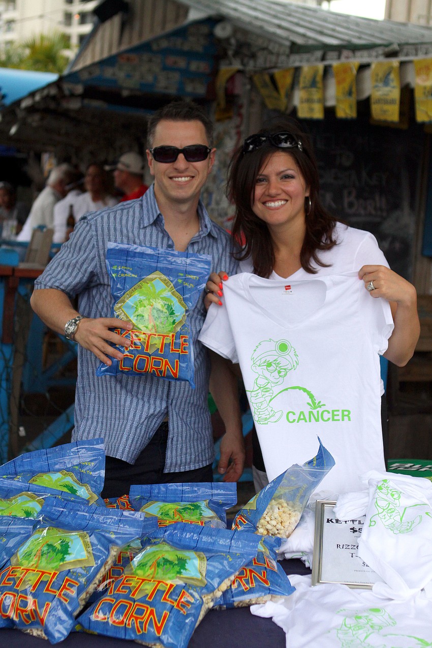 Richard Dahm holds up a bag of kettle corn while Yvonne Franco shows of the custom t-shirts made for the Siesta Gladiator Charity Challenge, Saturday, April 14, at SKOB.