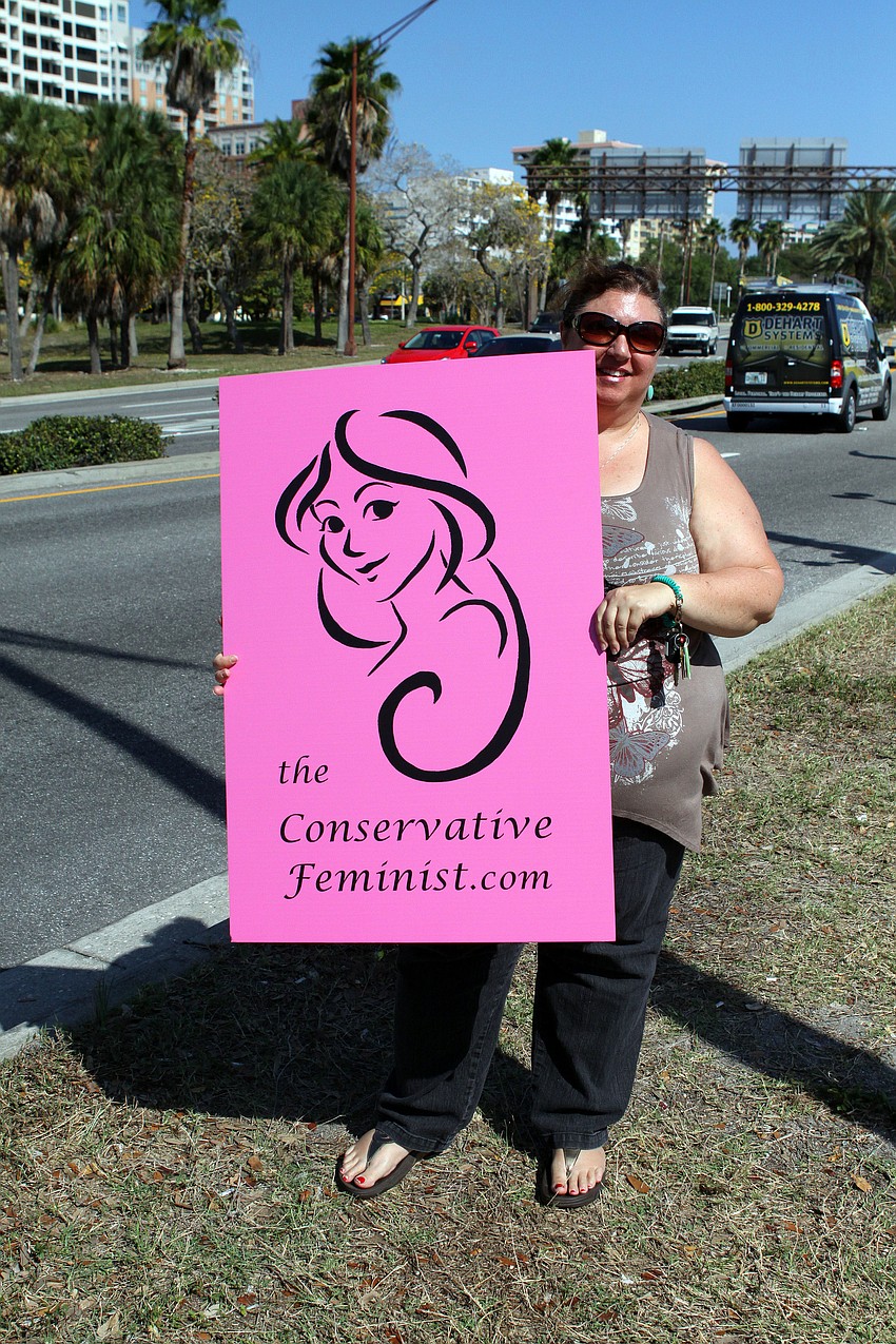 Chrissy Blevio of the Tea Party of 13 Patriots Inc. and the Conservative Feminist holds up a sign along 41, Friday, March 23.
