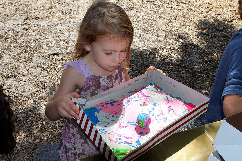 Annabelle Dawson, 4, has fun decorating a paper butterfly by rolling a golf ball through different colors of paint.