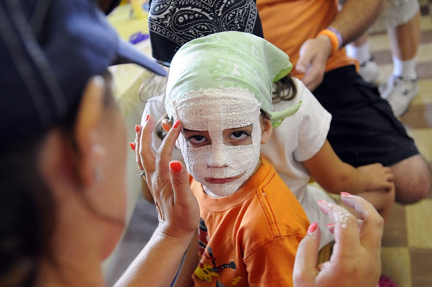 Four-year-old Donovan Olampo gets the finishing touches put on his mummy mask.