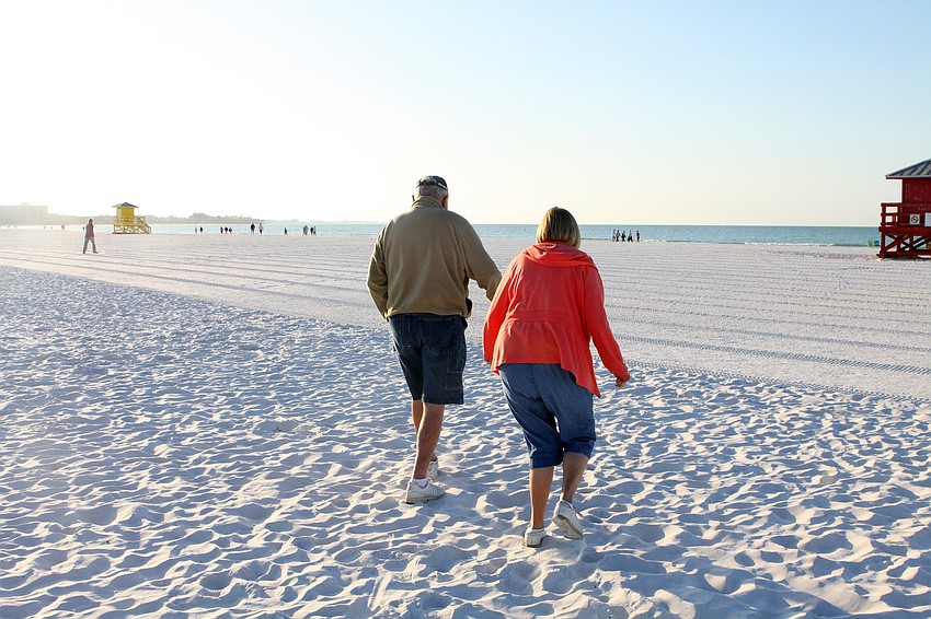 Don and Anita Glogovsky make their way down the beach for the Senior Beach Walk, Wednesday morning on Siesta Key Beach.